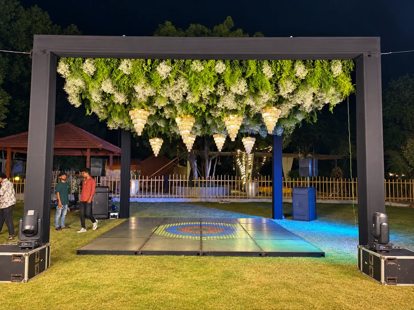 Black framed dance floor with greenery and chandeliers