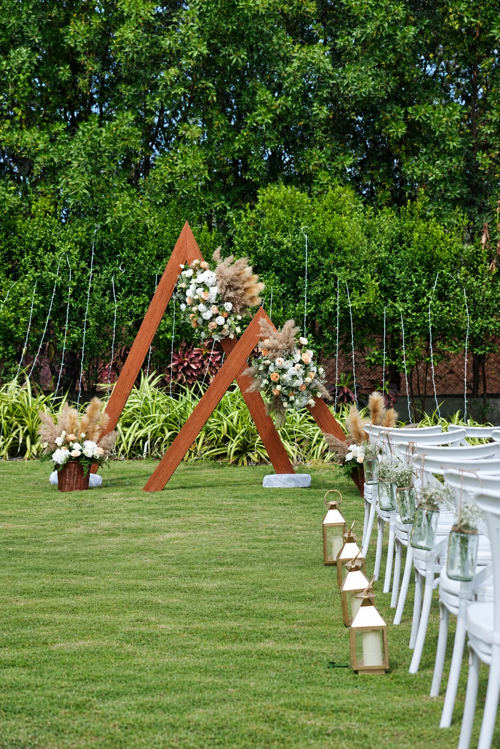 Triangular wooden ceremony frames with pampas grass, flowers and lanterns