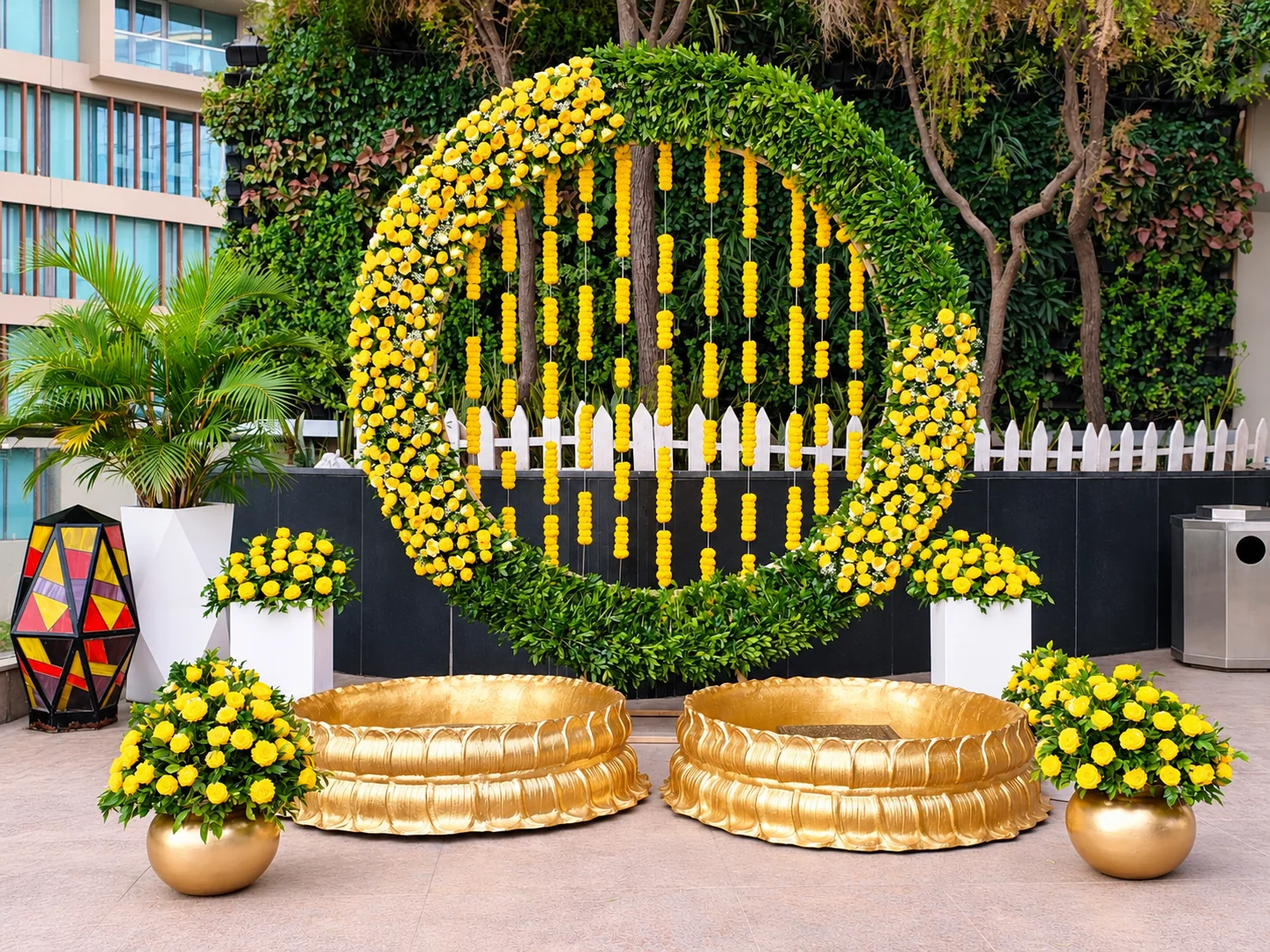 Circular yellow marigold backdrop with brass haldi bowls