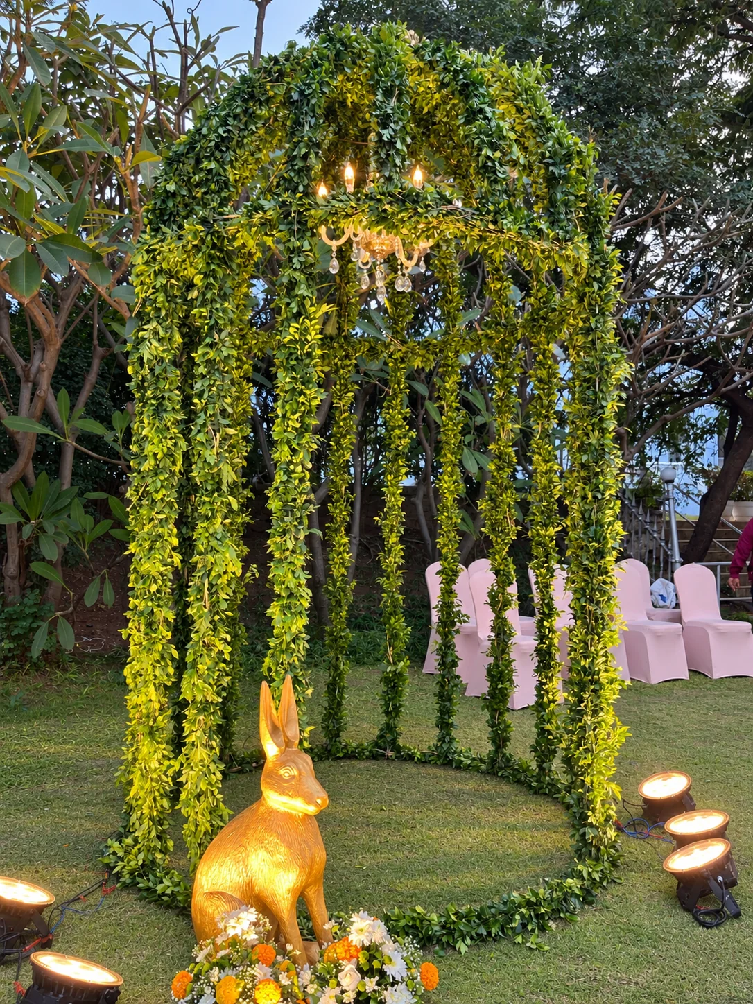 Greenery, chandeliers and gold ornaments beside celebration seating