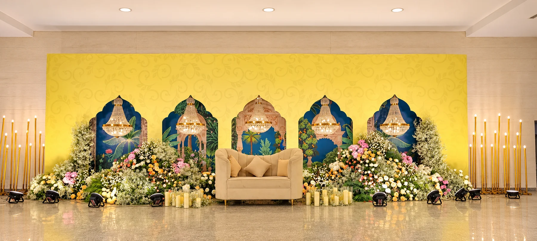 Yellow reception arches with blue motifs, chandeliers and a white sofa