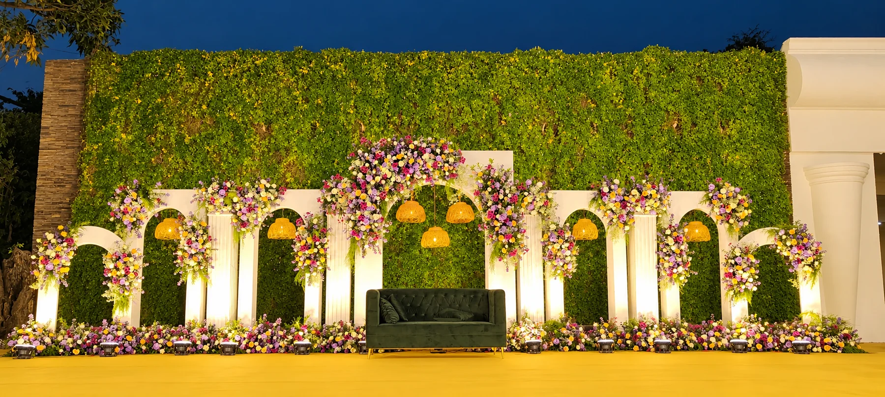 White reception arches with lilac and yellow flowers at night