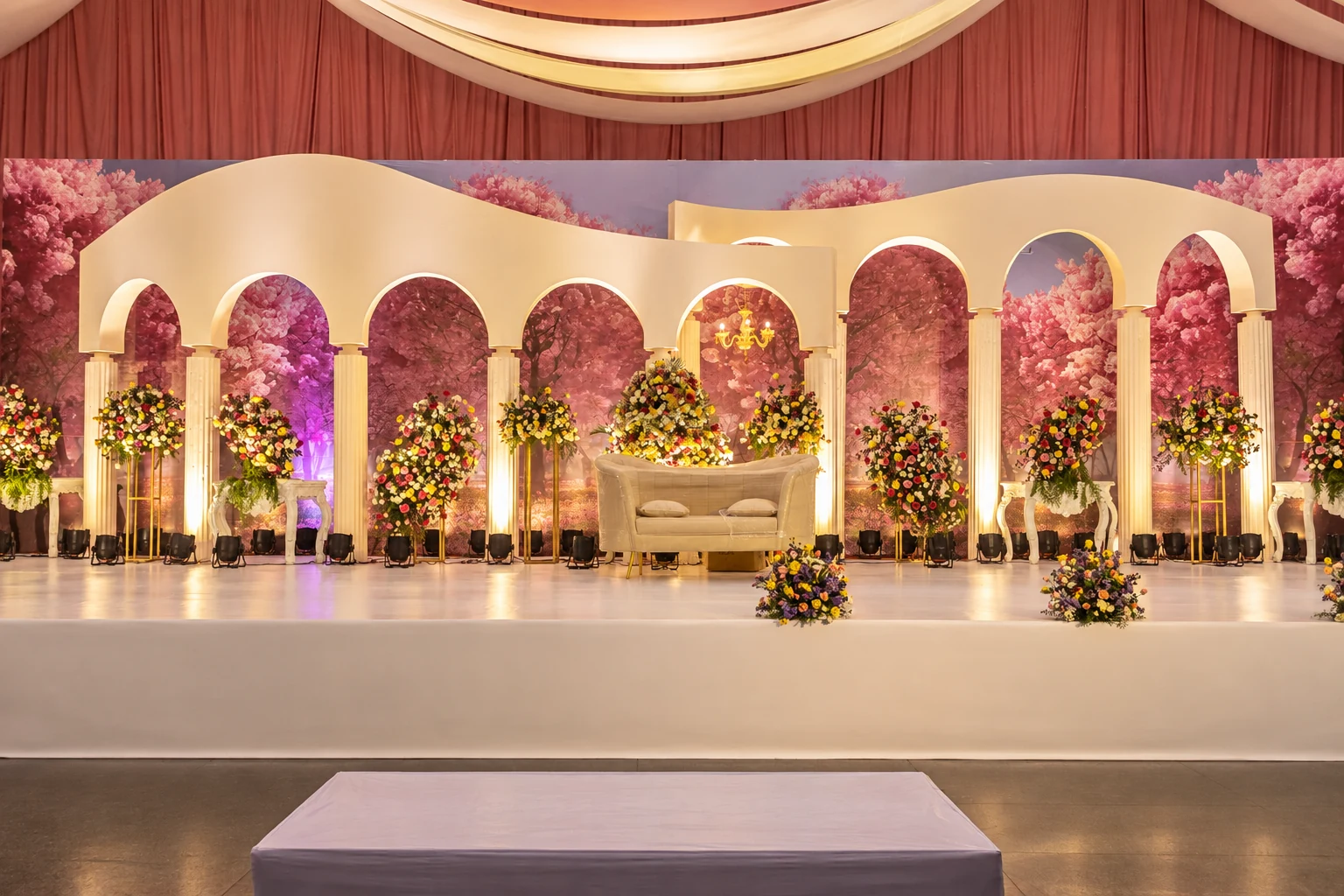 Pink arched reception stage with abundant floral arrangements
