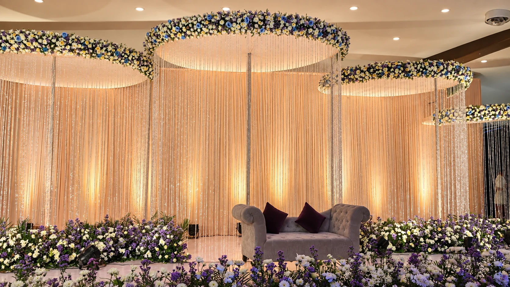 Peach draped reception stage with hanging floral rings