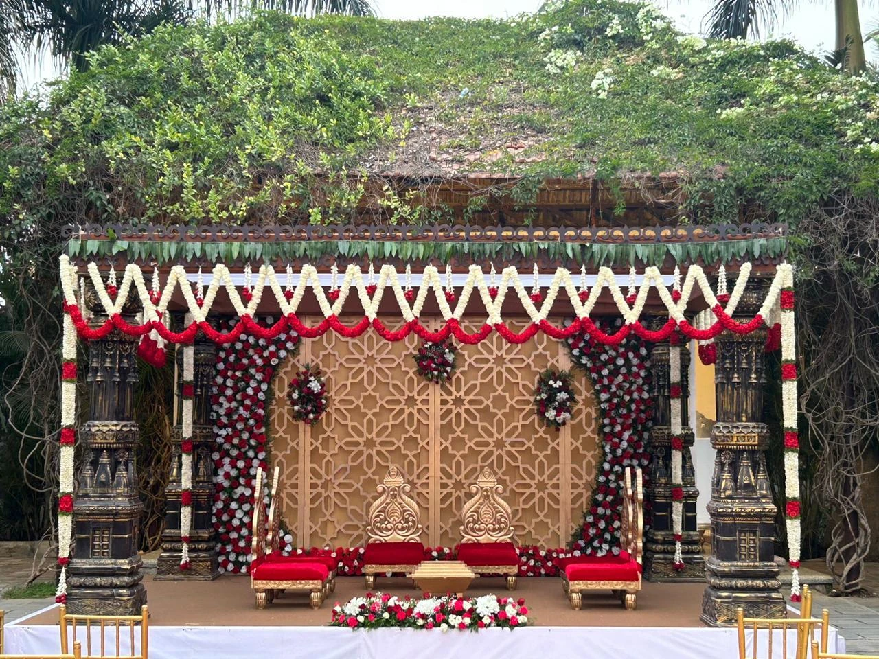 Tamara wedding mandap decorated with red and ivory garlands